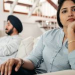 Avoiding Pitfalls - Sad young Indian woman avoiding talking to husband while sitting on sofa
