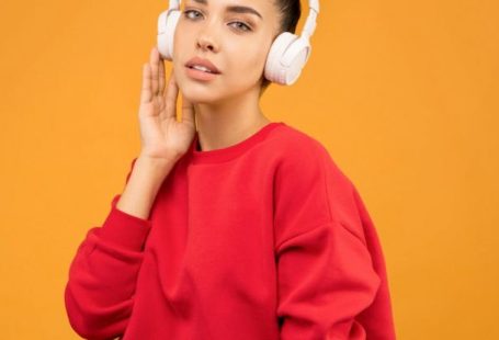 Trends Update - Woman in Red Sweatshirt and Blue Jeans Wearing White Headphones