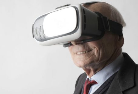 Interactive Content - Smiling elderly gentleman wearing classy suit experiencing virtual reality while using modern headset on white background