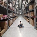 Inventory Management - Person Sitting on Ground Between Brown Cardboard Boxes
